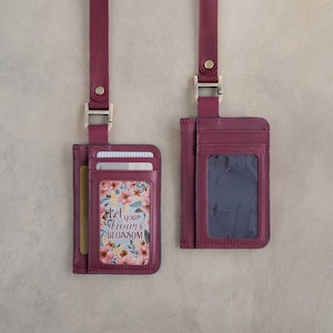 May include: Two burgundy leather cardholders with matching lanyards. One cardholder displays a floral design with the text "Let your dreams blossom." The other has a clear ID window. Both have silver-tone hardware.