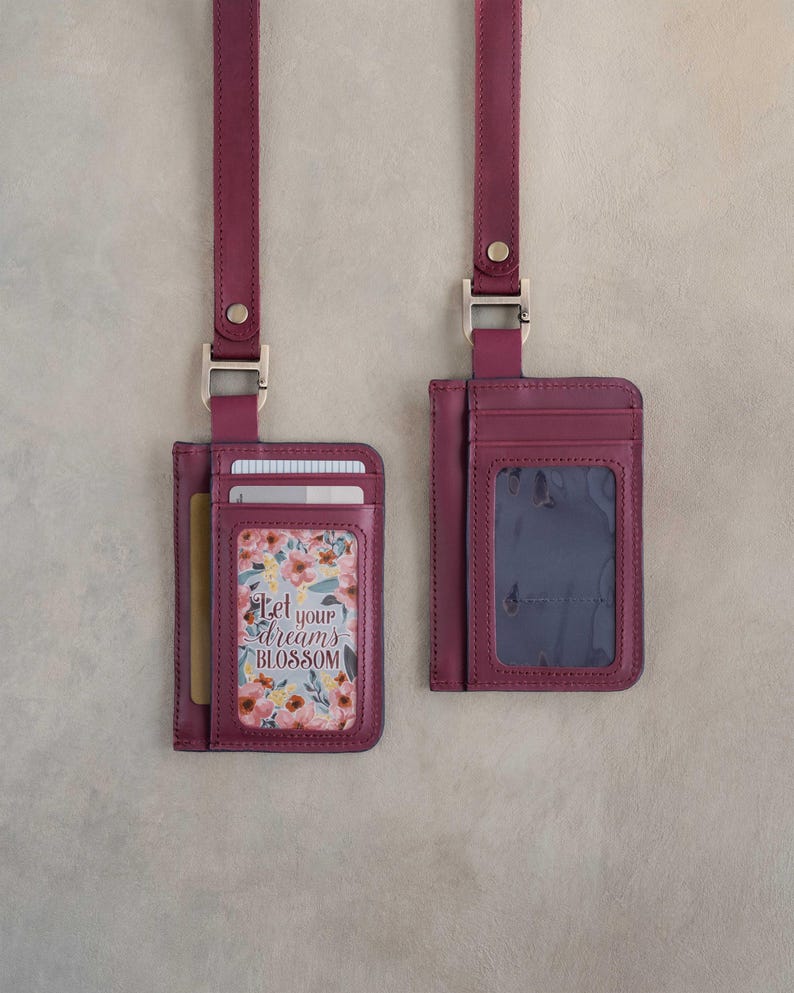May include: Two burgundy leather cardholders with matching lanyards. One cardholder displays a floral design with the text "Let your dreams blossom." The other has a clear ID window. Both have silver-tone hardware.