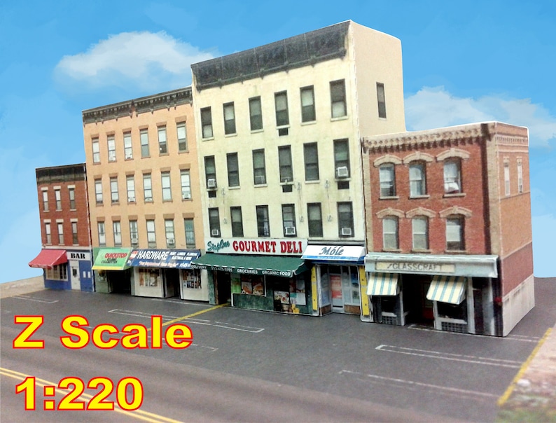 Peut inclure: Mod&egrave;le d'une rue de ville avec cinq b&acirc;timents en briques, chacun avec une vitrine. Les vitrines ont des auvents et des enseignes, dont "Gourmet Deli", "Hardware", "Bar", "Grocery" et "Glasscraft". Les b&acirc;timents sont &agrave; l'&eacute;chelle Z, soit 1:220.