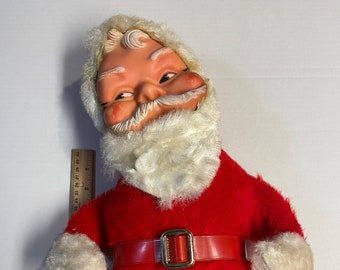 May include: Vintage Santa Claus doll with a red plush suit, white faux fur trim, and a plastic face. The doll has a red belt with a gold buckle. A ruler is next to the doll, measuring up to 12 inches.