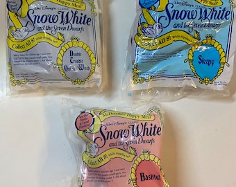 May include: Three McDonald's Happy Meal toys featuring Disney's Snow White and the Seven Dwarfs. Each toy is sealed in a clear plastic bag. The bags have the names of the characters: Double Trouble Queen/Witch, Sleepy, and Bashful.