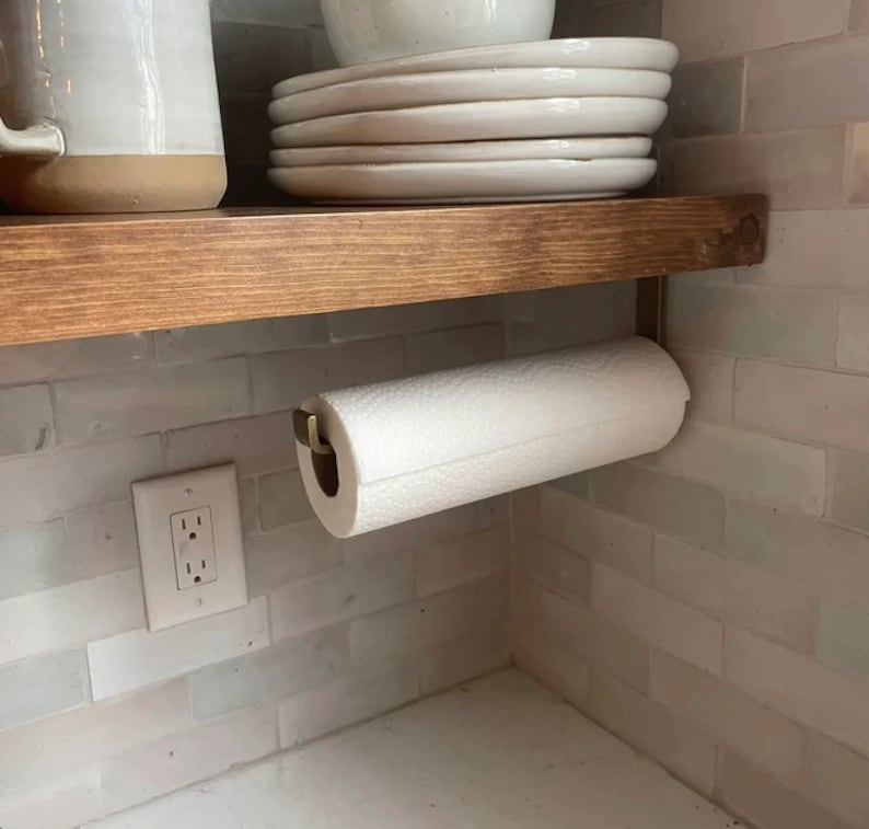 kitchen with brass paper towel holder mounted under wood shelving and white dishes