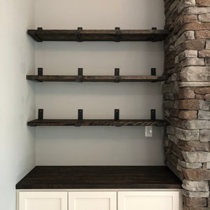 bar nook with three dark wood shelves supported by heavy duty metal shelf brackets next to a fireplace