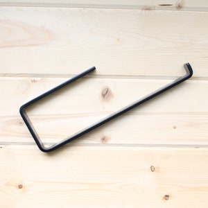 metal paper towel holder with open arm and front lip on wood background