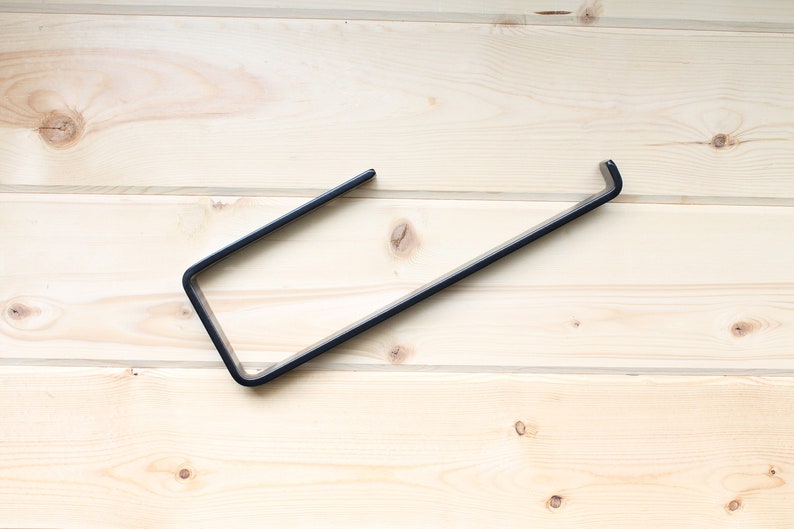 metal paper towel holder with open arm and front lip on wood background