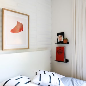 Kids bedroom with a bed and artwork plus two small floating book ledge shelves mounted on wall. They are displaying children's books.