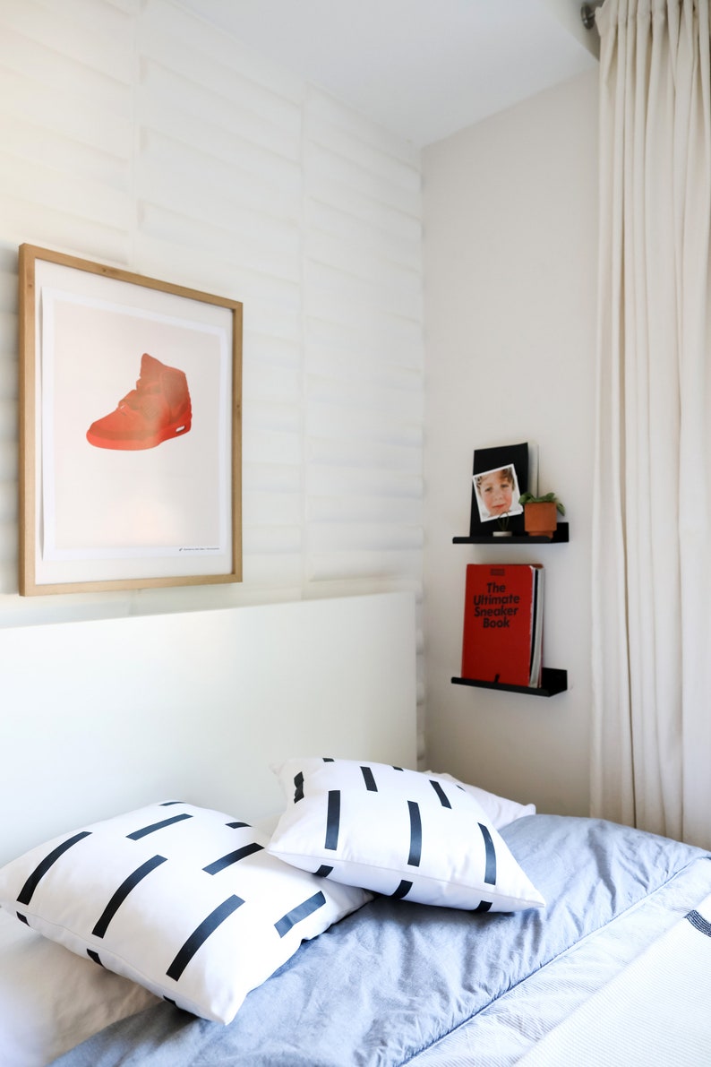 Kids bedroom with a bed and artwork plus two small floating book ledge shelves mounted on wall. They are displaying children's books.