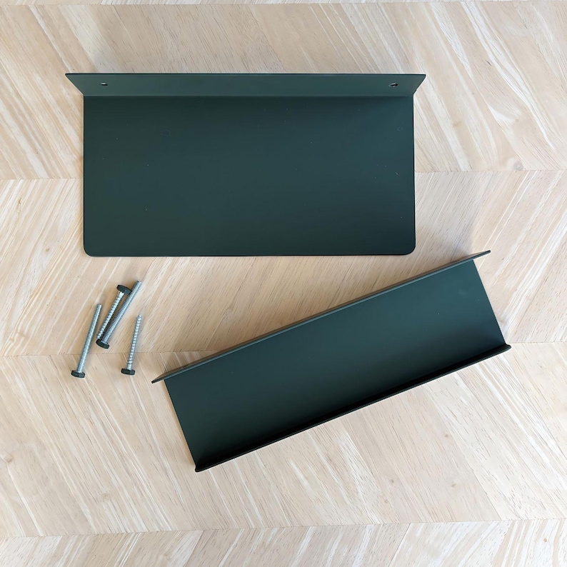 There are two olive green shelves one a flat shelf and one a display ledge laying on a wood background. There are matching green bolts.