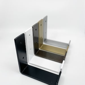 Five heavy duty metal J style hook brackets lined up in different powder coated finishes: black, white, raw steel, brass, silver