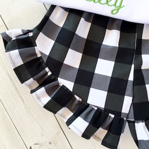 May include: Black and white checkered shorts with a ruffled hem. The shorts are made of a soft, lightweight fabric and are perfect for summer.