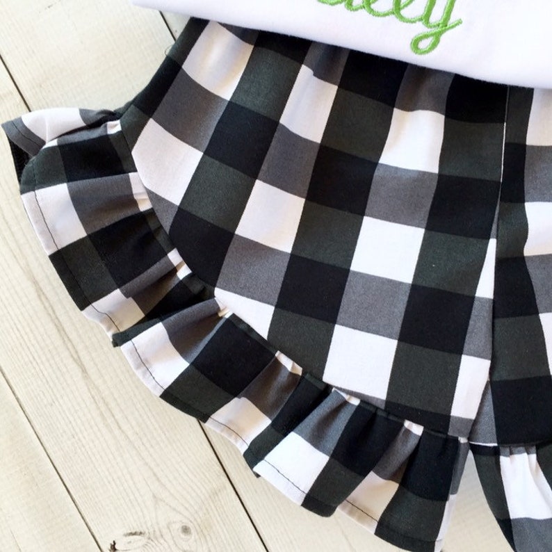 May include: Black and white checkered shorts with a ruffled hem. The shorts are made of a soft, lightweight fabric and are perfect for summer.