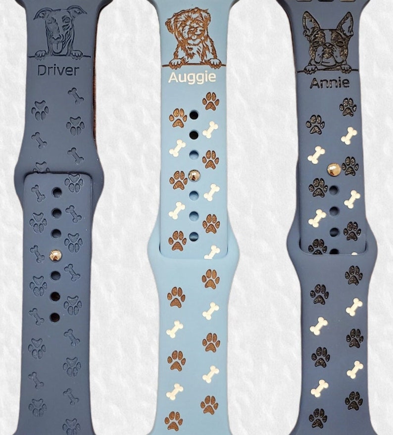 May include: Three blue and white patterned Apple Watch bands with personalized dog portraits and names: Driver, Auggie, and Annie.