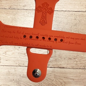 Pode incluir: Pulseira de rel&oacute;gio de silicone laranja com um design de cruz e uma cita&ccedil;&atilde;o de 1 Tessalonicenses 5:23-24: "Agora, que o Deus da paz vos santifique a v&oacute;s mesmos completamente, e que o vosso esp&iacute;rito, alma e corpo sejam preservados irrepreens&iacute;veis para a vinda do nosso Senhor Jesus Cristo. Fiel &eacute; aquele que vos chama, ele tamb&eacute;m o far&aacute;."