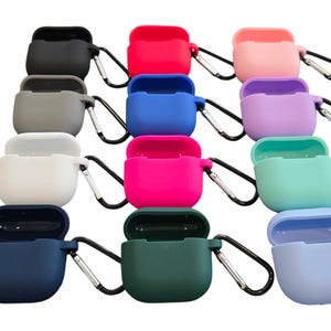May include: Assortment of 10 silicone Airpod cases in various colours, including black, grey, white, blue, pink, purple, green, and light blue. Each case has a carabiner clip attached.