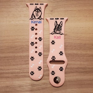 May include: Two pink Apple Watch bands with paw print and bone designs. The band on the left has a black and white husky dog image and the text "Kenai". The band on the right has a black and white German Shepherd dog image and the text "Kali".