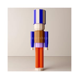 May include: A blue and white striped papercraft nutcracker with brown and purple accents. The nutcracker is standing on a white surface.