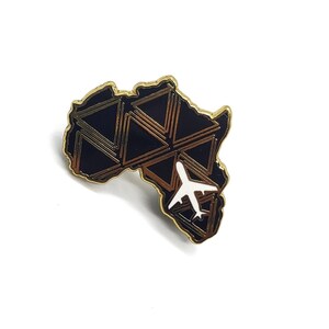 May include: Gold-colored pin with a black and gold outline of the continent of Africa. A white airplane is flying over the continent.