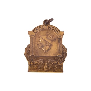 May include: A gold-colored metal medal with the words "Crestwood" and "1937" on it. The medal features a profile of a person wearing a winged hat.