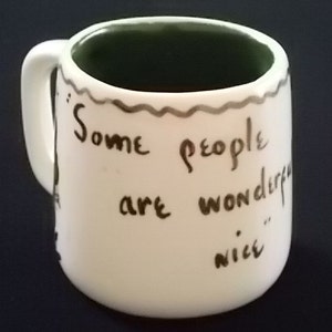 May include: White ceramic mug with a green rim and a handwritten message in black ink that reads "Some people are wonderful... nice".