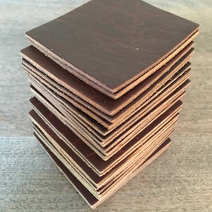 May include: A stack of brown leather squares, likely coasters or placemats, with a slightly rough texture.