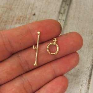 May include: Gold-toned metal toggle clasp with a round ring and a straight bar. The clasp is designed for jewelry making.