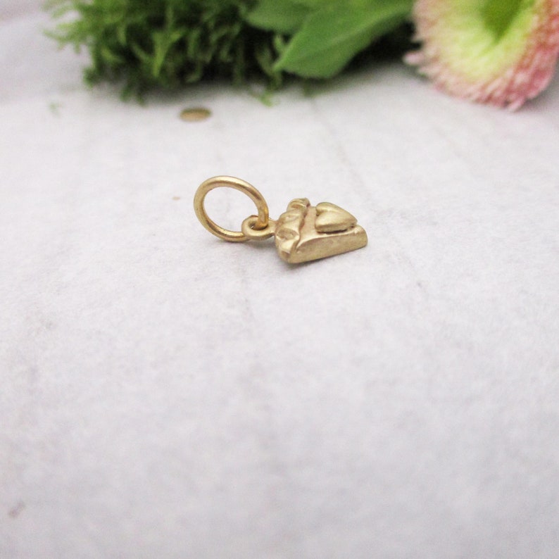 Puede incluir: Un peque&ntilde;o dije dorado con forma de tel&eacute;fono antiguo. El dije tiene un anillo en la parte superior para sujetarlo a un collar o pulsera. El dije del tel&eacute;fono est&aacute; detallado con un auricular y botones.