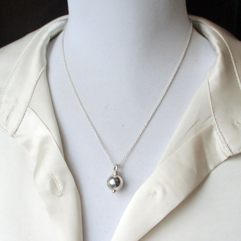 May include: A silver chain necklace with a round silver pendant.