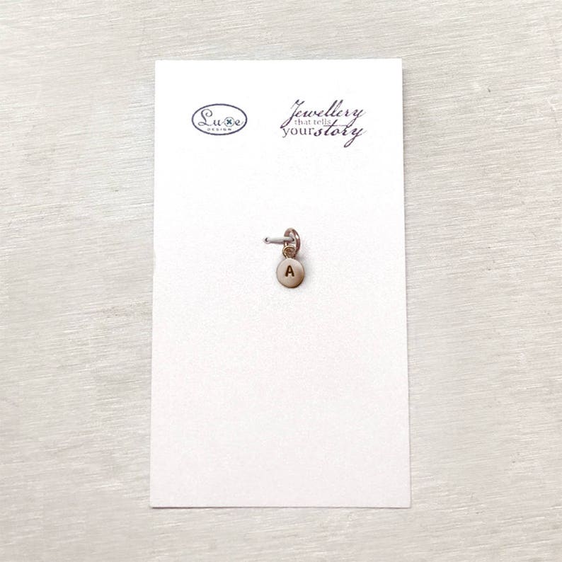 May include: A silver charm with the letter A on a white card with the text "Jewellery that tells your story" and the logo "Luxe Design".