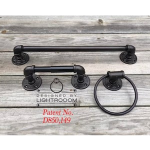 May include: A set of black industrial pipe bathroom fixtures, including a towel bar, toilet paper holder, and towel ring. The fixtures are mounted on round, black flanges. The text "DESIGNED BY LIGHTROOOM" and "Patent No. D850,149" are visible.