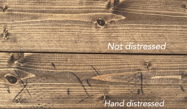 May include: Close-up of two wooden planks with a brown stain. The top plank is labeled "Not distressed," while the bottom plank is labeled "Hand distressed," showcasing the difference in texture and appearance.