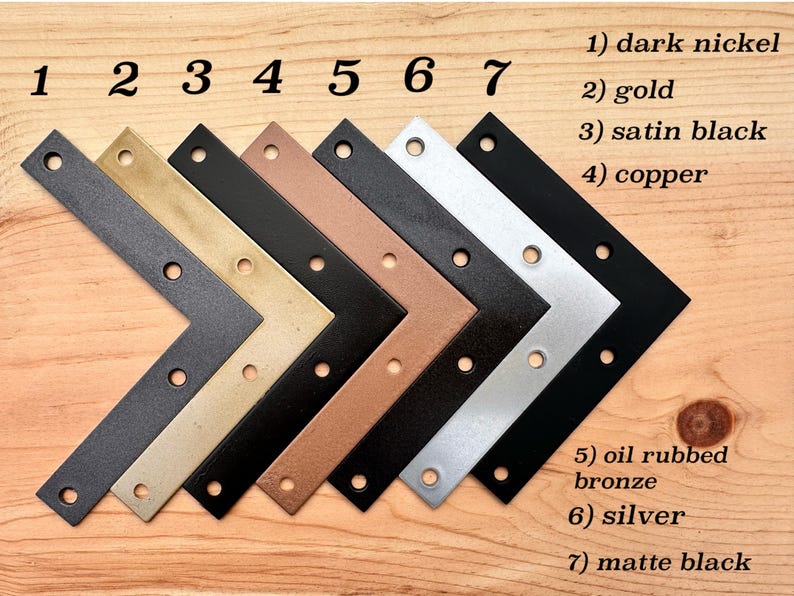 May include: An assortment of seven L-shaped metal brackets in various finishes, including dark nickel, gold, satin black, copper, oil-rubbed bronze, silver, and matte black. Each bracket has pre-drilled holes for mounting.