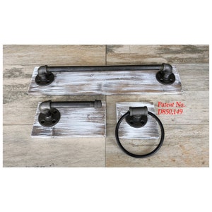 May include: A set of industrial-style bathroom fixtures. The set includes a towel bar, a hand towel holder, and a towel ring. Each piece features black metal pipes and fittings mounted on distressed white-painted wooden boards. Patent No. D850,149 is visible.