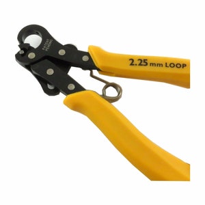 May include: Jewelry-making pliers with yellow handles and black jaws. The text "2.25 mm LOOP" is printed on one handle. The pliers have a spring and a loop-forming head. The tool is designed for creating consistent loops in wire.