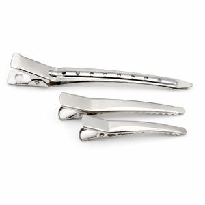 May include: Three silver-colored metal hair clips of varying lengths. The longest clip features a series of small circular cutouts along the top edge, while the two shorter clips have a smooth, solid surface and serrated edges for gripping hair.