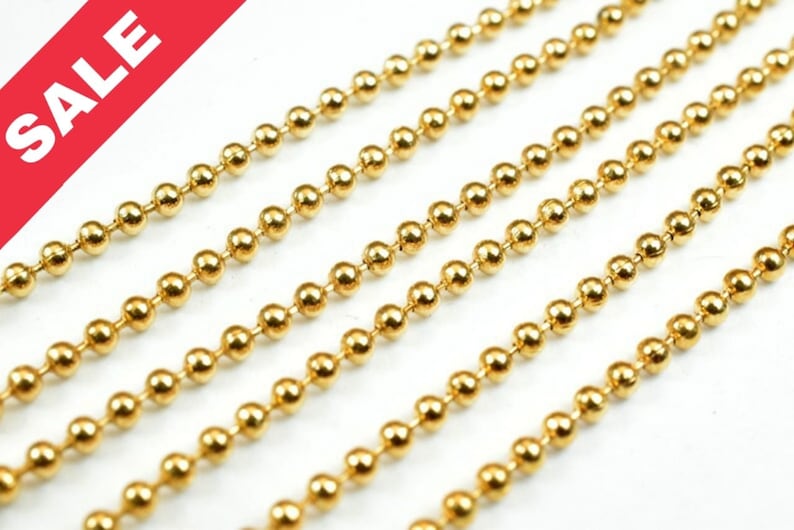 May include: Gold ball chain, a type of jewelry chain made of small, round metal balls connected by links. The chain is shown in multiple strands, highlighting its smooth, shiny surface.