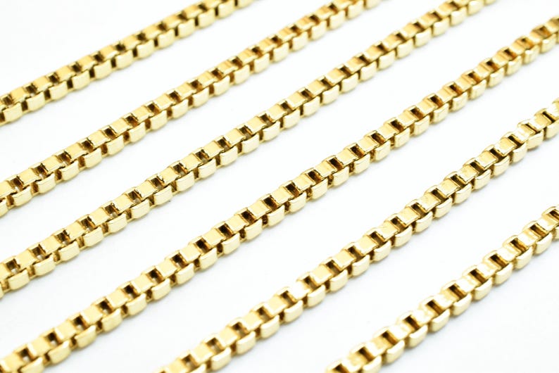 A close-up view of several gold-colored metal chains arranged in a repeating pattern.