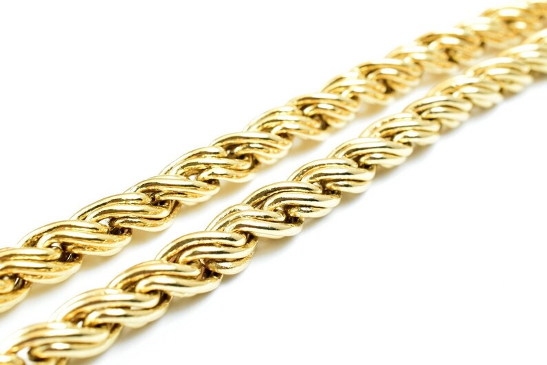 May include: A close-up of a gold rope chain necklace. The chain is made of thick, interwoven links, creating a textured and luxurious look.