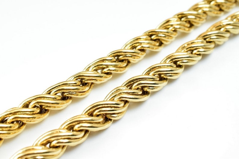 May include: A close-up of a gold rope chain necklace. The chain is made of thick, interwoven links, creating a textured and luxurious look.