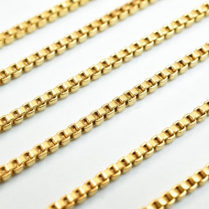 Puede incluir: Cuatro hebras de collar de cadena de eslabones de oro, dispuestas en l&iacute;neas paralelas sobre una superficie blanca.