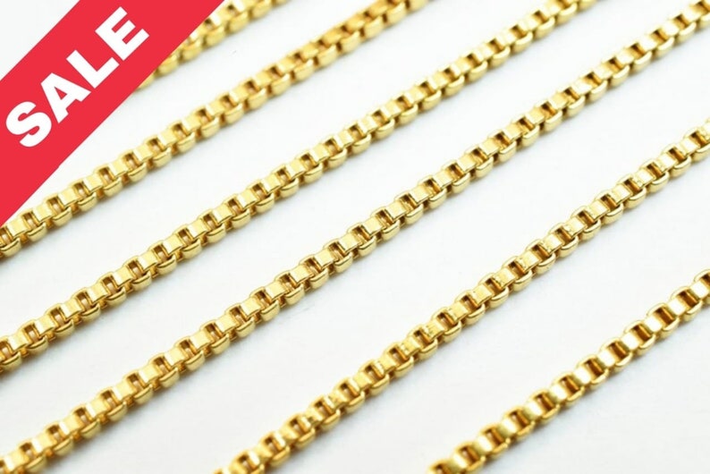 Puede incluir: Cuatro hebras de cadena de oro, cada una con un patr&oacute;n de cadena de caja, se colocan sobre una superficie blanca. Las cadenas son todas de la misma longitud y anchura.