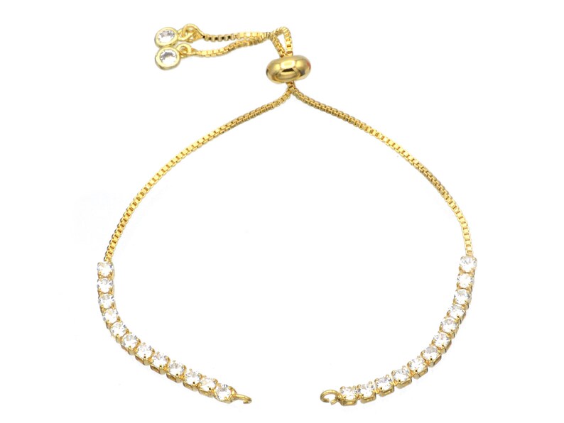 Puede incluir: Un brazalete de cadena dorada con cierre deslizante y una fila de piedras de circonita c&uacute;bica transparentes.