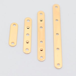 May include: Four gold-colored metal connector bars of varying lengths, each with evenly spaced holes for attaching components. The bars are arranged vertically against a light gray background, showcasing their polished finish and design.