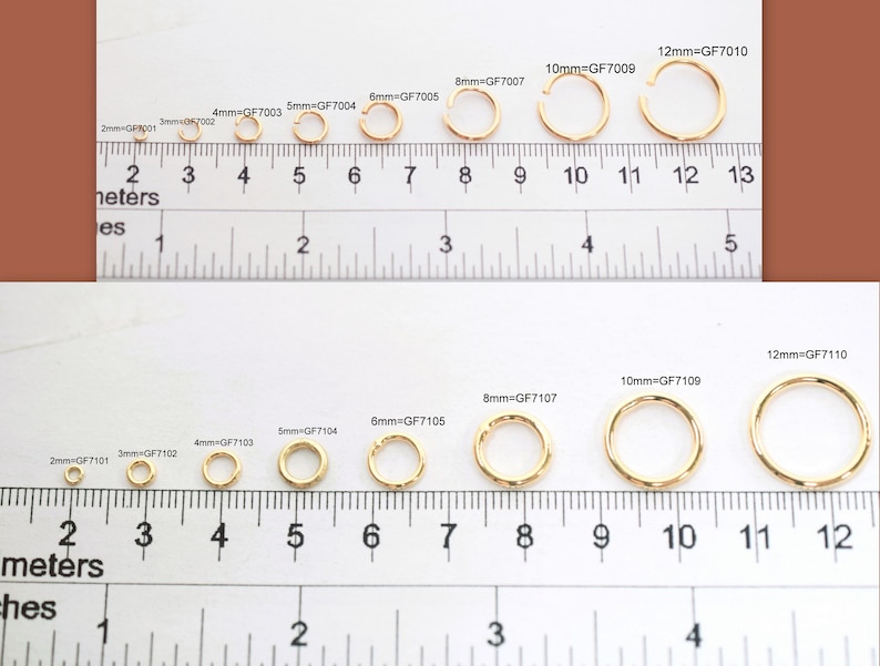 May include: A collection of gold-colored metal jump rings and closed rings arranged by size from 2mm to 12mm along a ruler. The top row shows open jump rings labeled 2mm=GF7001 through 12mm=GF7010, while the bottom row shows closed rings labeled 2mm=GF7101 through 12mm=GF7110.