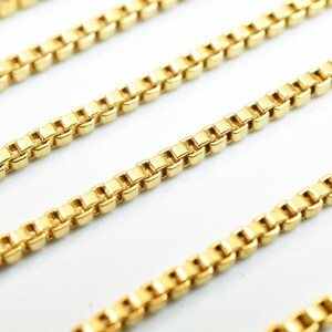 Puede incluir: Primer plano de un collar de cadena de oro con un dise&ntilde;o de cadena de caja. La cadena est&aacute; hecha de peque&ntilde;os eslabones cuadrados.