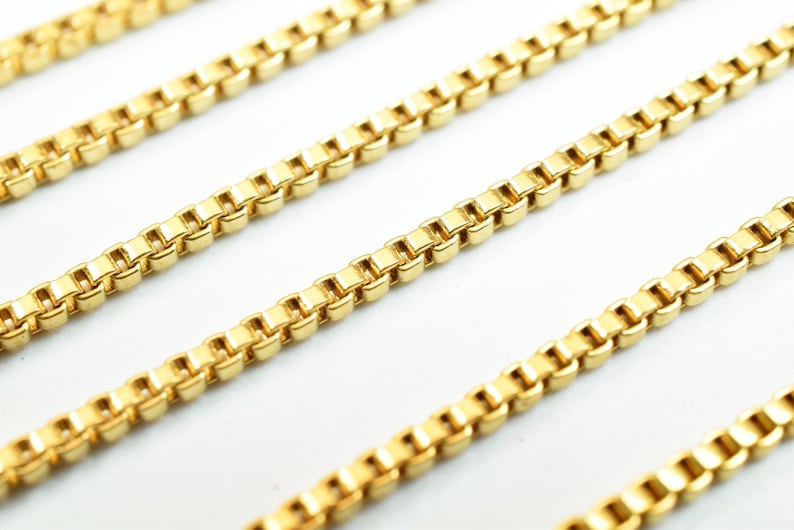 Puede incluir: Primer plano de un collar de cadena de oro con un dise&ntilde;o de cadena de caja. La cadena est&aacute; hecha de peque&ntilde;os eslabones cuadrados.