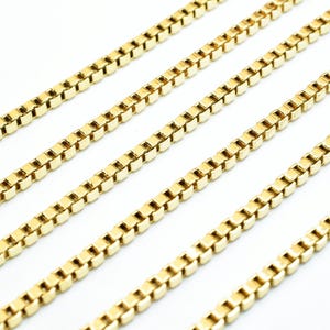 A close-up image of several gold-colored metal chains arranged in a diagonal line against a white background.
