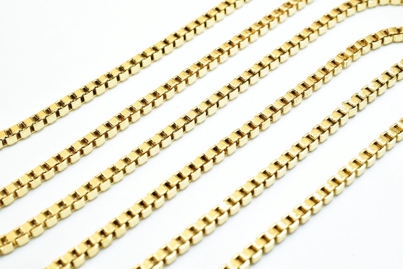 A close-up image of several gold-colored metal chains arranged in a diagonal line against a white background.