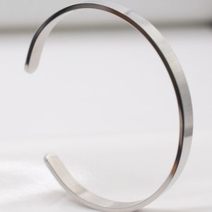 K&ouml;nnte beinhalten: Ein minimalistisches silbernes Armband. Das offene Design hat eine glatte, polierte Oberfl&auml;che. Dieses schlichte, elegante St&uuml;ck ist ein vielseitiges Accessoire f&uuml;r den Alltag. Der Durchmesser des Armbands betr&auml;gt ca. 6,35 cm.