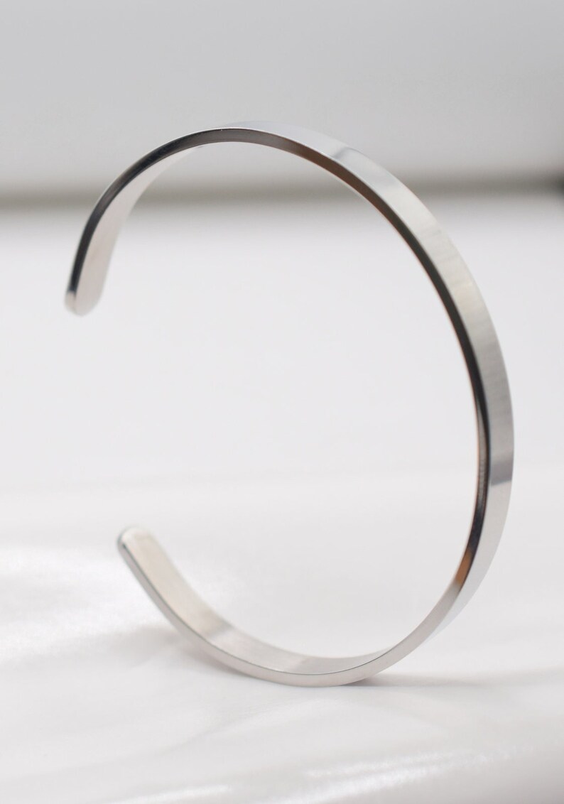 K&ouml;nnte beinhalten: Ein minimalistisches silbernes Armband. Das offene Design hat eine glatte, polierte Oberfl&auml;che. Dieses schlichte, elegante St&uuml;ck ist ein vielseitiges Accessoire f&uuml;r den Alltag. Der Durchmesser des Armbands betr&auml;gt ca. 6,35 cm.