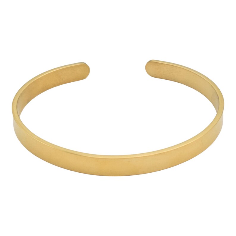 K&ouml;nnte beinhalten: Ein goldfarbenes Armreif-Armband. Das offene Armband hat eine glatte, flache Oberfl&auml;che und eine abgerundete Form. Der Schmuck ist ein schlichtes, minimalistisches Design.